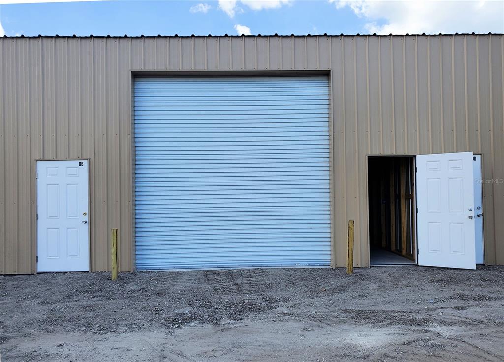 The exterior of a metal building features a large roll-up door between two entry doors — 532 N BLUFORD AVENUE, OCOEE, FL