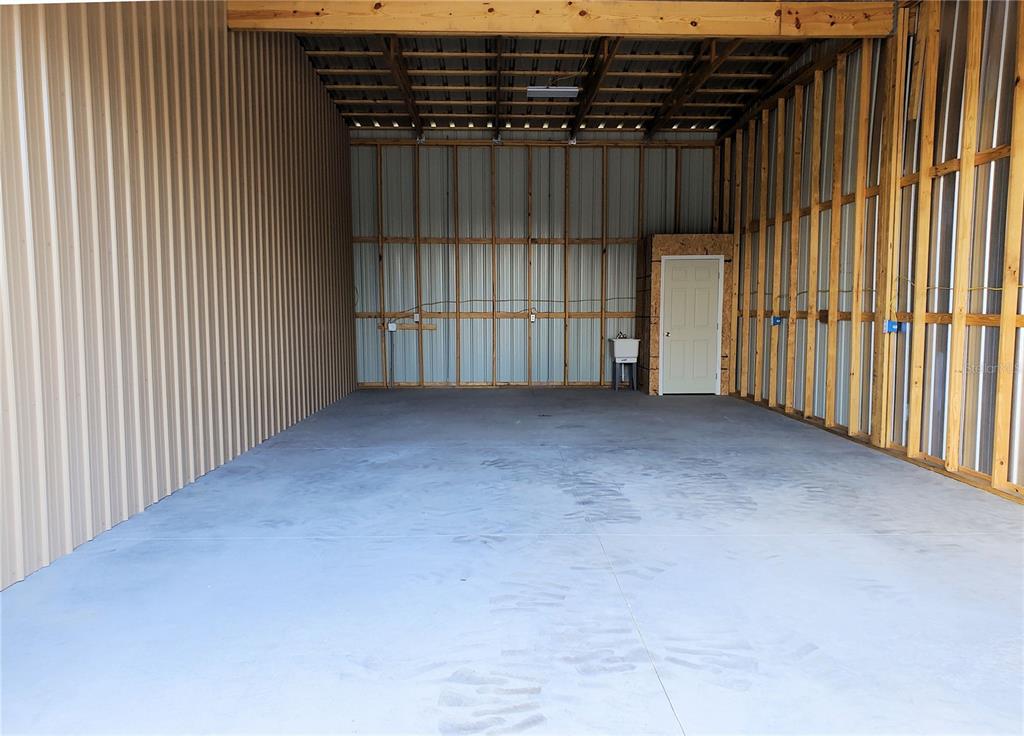 An unfinished metal workshop features a concrete floor, exposed wood framing, and a utility sink — 532 N BLUFORD AVENUE, OCOEE, FL