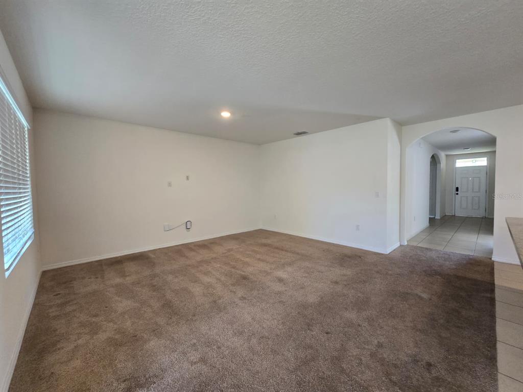 A carpeted living room with white walls and a view toward the front entryway — 1895 CASSIDY KNOLL DRIVE, KISSIMMEE, FL