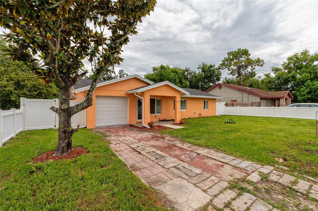 A single-story orange house with a white garage door and a paver driveway — 1015 MACK AVENUE, ORLANDO, FL