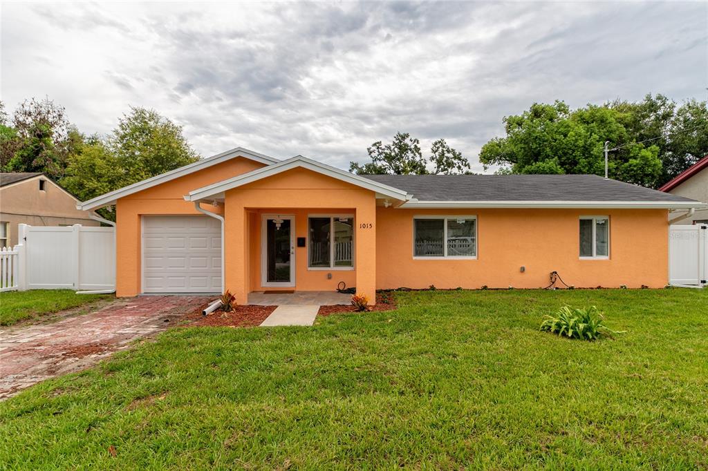 A single-story orange house with a white garage door and a front entrance porch — 1015 MACK AVENUE, ORLANDO, FL