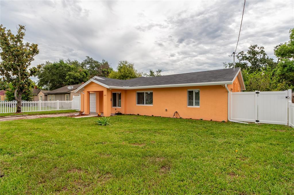 A single-story orange house with a white fence and a grassy front yard — 1015 MACK AVENUE, ORLANDO, FL