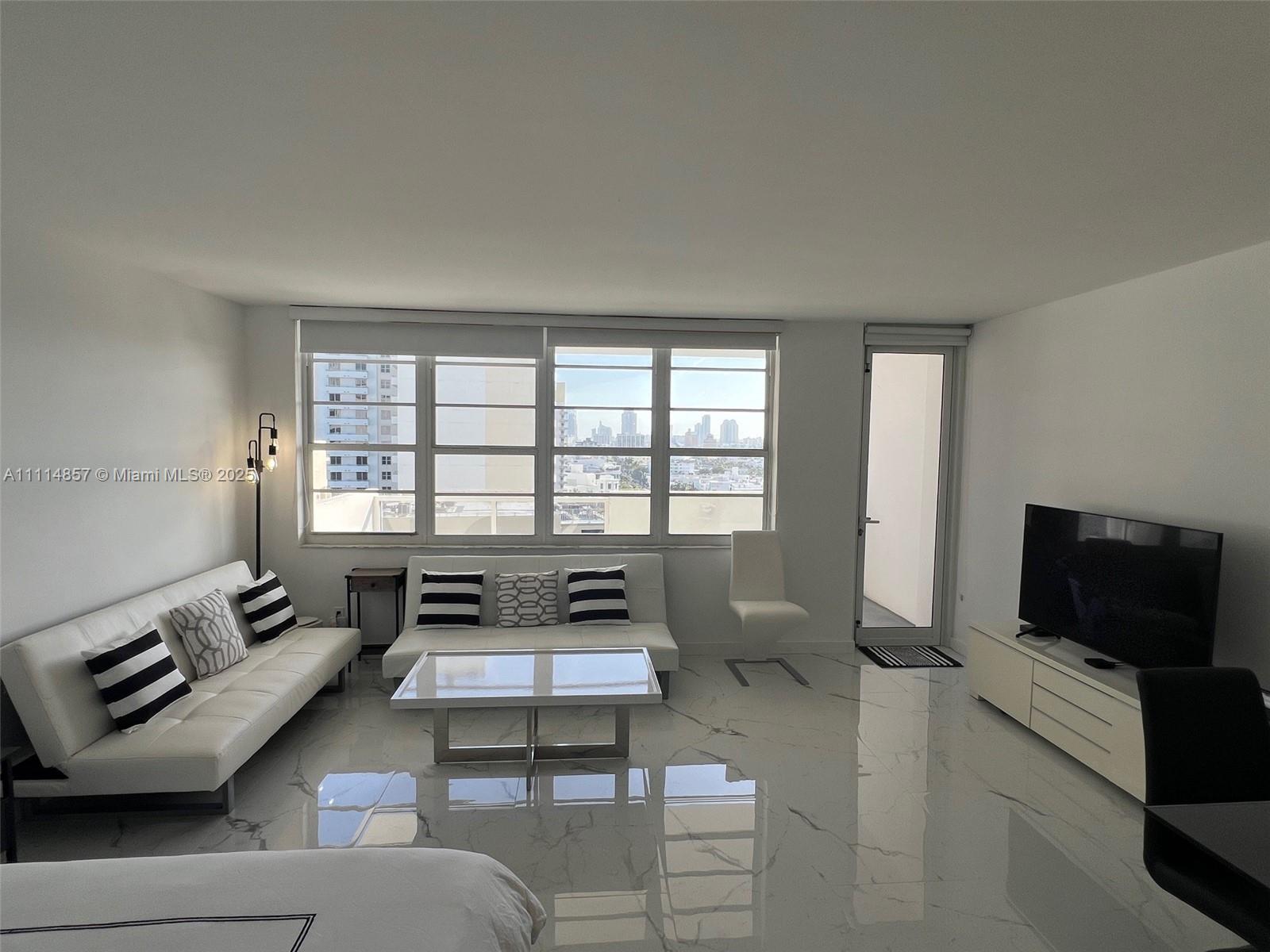 A living room features white sofas, a glass coffee table, and marble-look tile flooring — 100 Lincoln Rd # 1207, Miami Beach FL 33139, MIAMI BEACH, FL