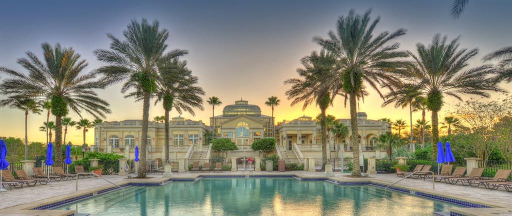 A swimming pool sits in front of a large, multi-story building with palm trees — 698 MAHOGANY RUN, PALM COAST, FL