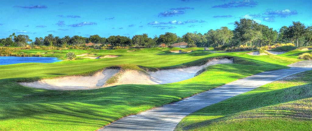 A golf course fairway features a sand bunker, a paved path, and a nearby lake — 698 MAHOGANY RUN, PALM COAST, FL