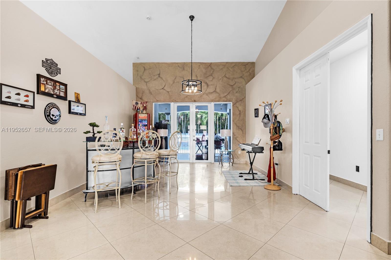 A room with tile floors, a home bar, and a textured stone accent wall — 12969 SW 220th Ter, Miami FL 33170, MIAMI, FL