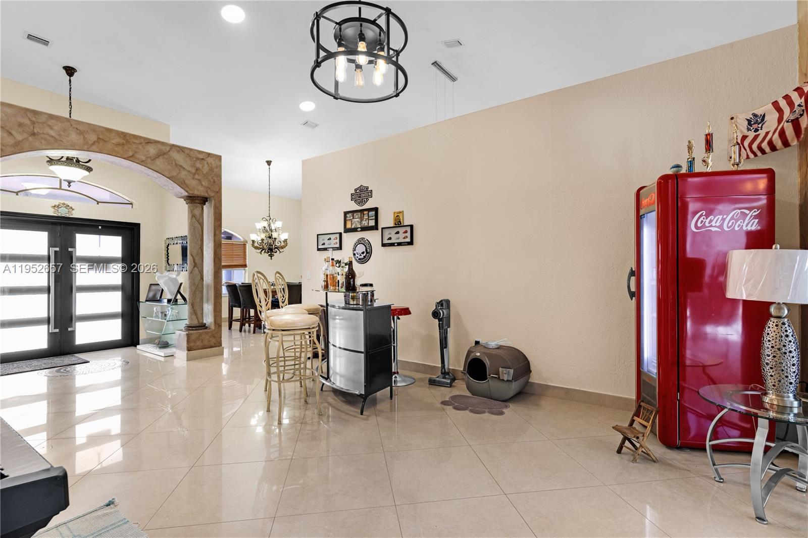 A room with tile floors features a home bar, a Coca-Cola refrigerator, and lighting — 12969 SW 220th Ter, Miami FL 33170, MIAMI, FL