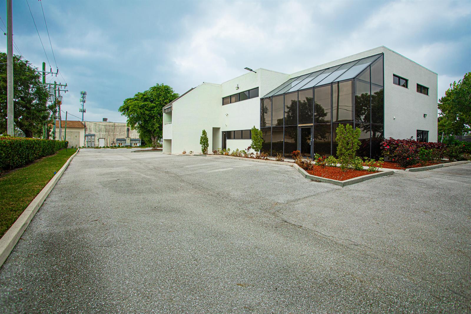 A two-story commercial building with a glass-enclosed atrium and an adjacent paved parking lot — 1700 Okeechobee Road, West Palm Beach FL 33409, WEST PALM BEACH, FL