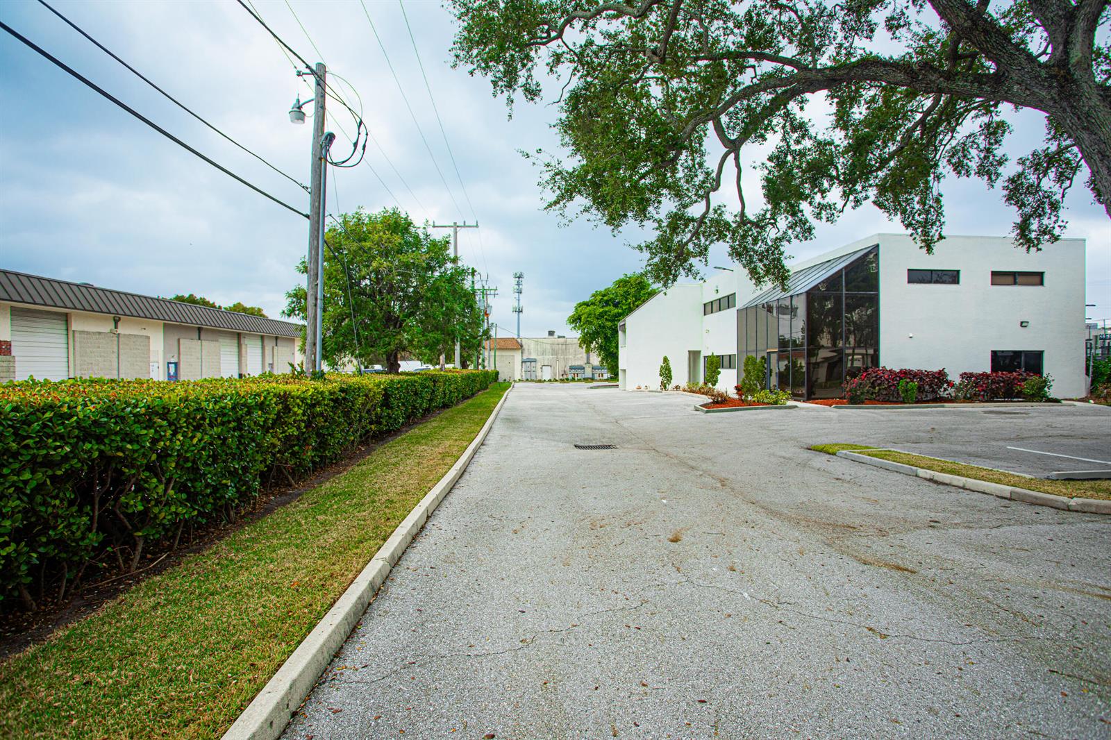 An exterior view of a commercial building with a parking lot and a landscaped hedge — 1700 Okeechobee Road, West Palm Beach FL 33409, WEST PALM BEACH, FL