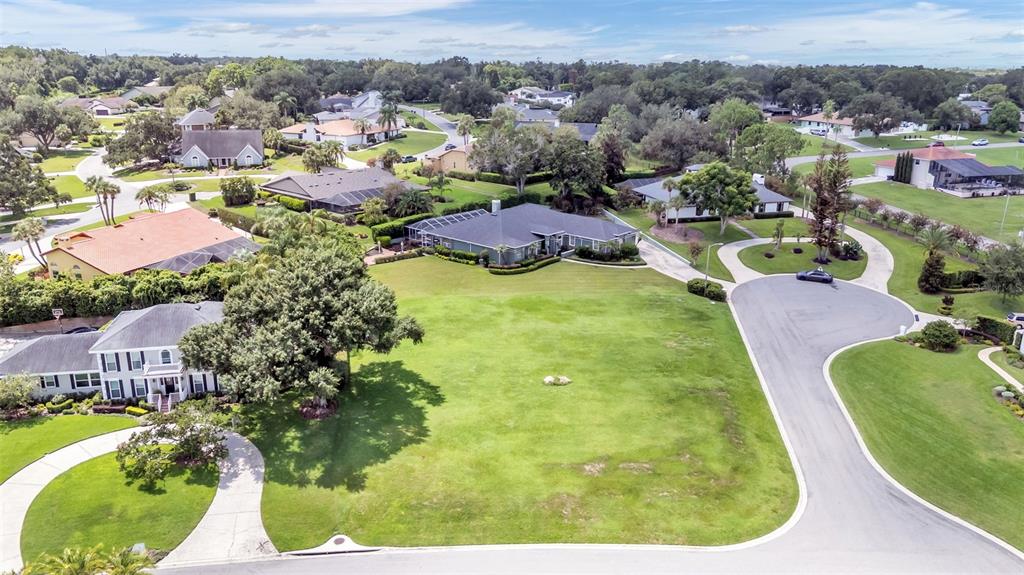 An aerial view shows a large, vacant grassy lot surrounded by suburban houses and streets — PIER PLACE DRIVE, LAKELAND, FL