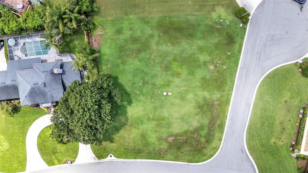 An aerial view shows a vacant residential lot situated next to a house with a pool — PIER PLACE DRIVE, LAKELAND, FL