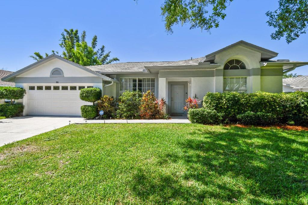 A single-story house with a white garage, gray trim, and a landscaped front yard — 915 BRITTANY PARK BOULEVARD, TARPON SPRINGS, FL