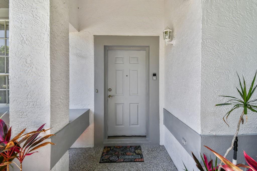 A gray front door with a welcome mat is set within a white stucco entryway — 915 BRITTANY PARK BOULEVARD, TARPON SPRINGS, FL