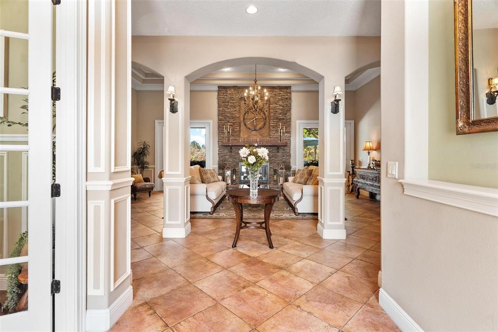 A tiled entryway leads into a living room featuring a stone fireplace and arched columns — 3001 ISOLA BELLA BOULEVARD, MOUNT DORA, FL