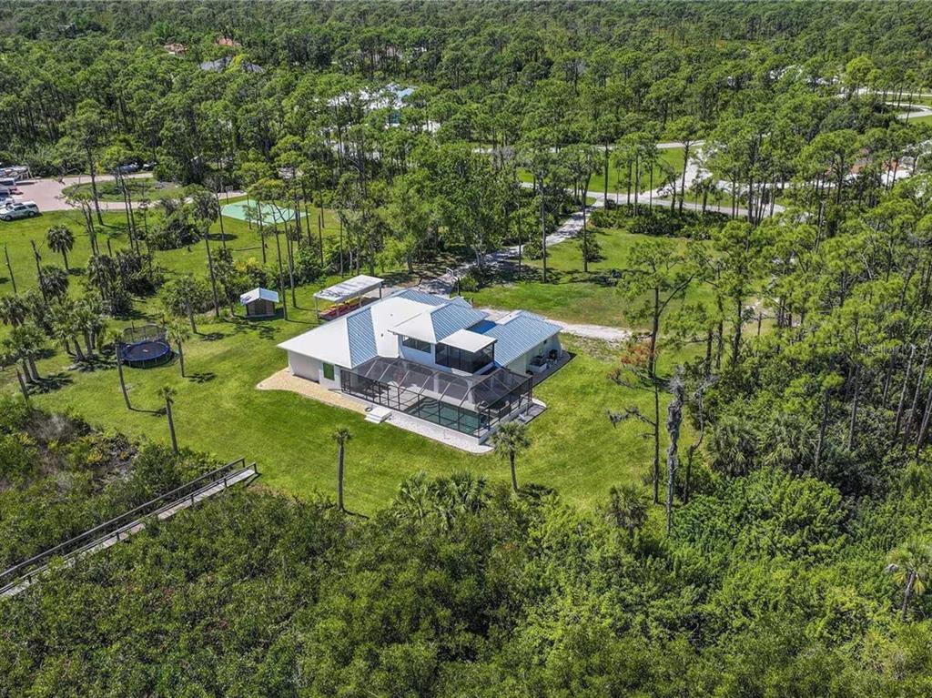 A paved driveway leads to a white house surrounded by trees and palm bushes — 18 RIVERFRONT DRIVE, VENICE, FL