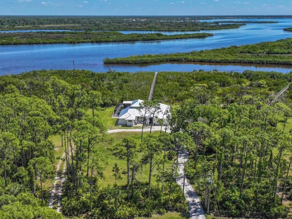 A single-story house with a metal roof, white stucco exterior, and a large front yard — 18 RIVERFRONT DRIVE, VENICE, FL