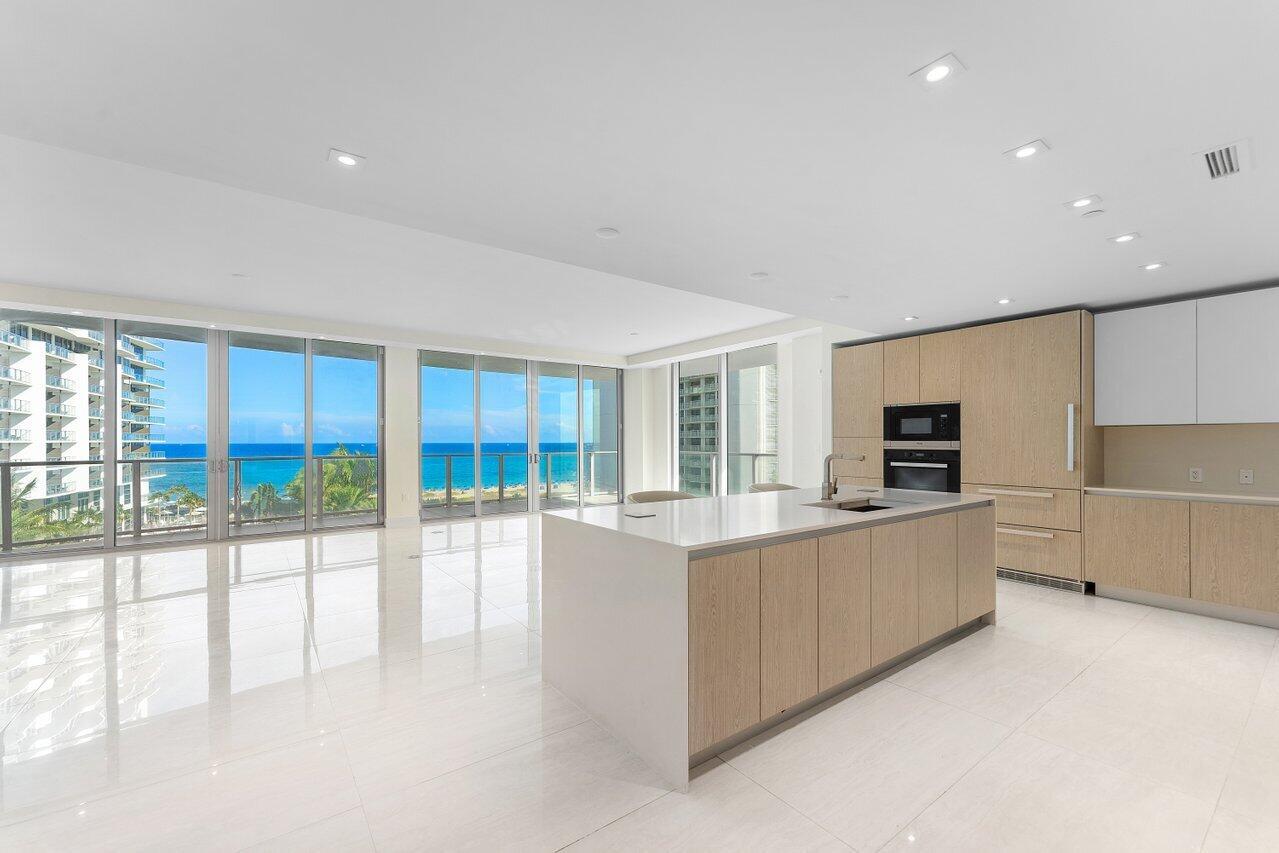 A modern kitchen with light wood cabinetry and a white island overlooks the ocean — 3100 N Ocean Drive # P705, Riviera Beach FL 33404, RIVIERA BEACH, FL