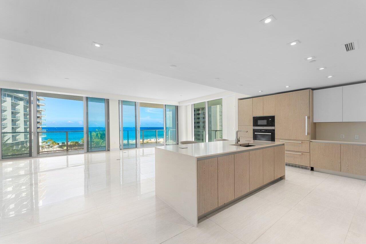A modern kitchen with a large island and light wood cabinets overlooks the ocean — 3100 N Ocean Drive # P705, Riviera Beach FL 33404, RIVIERA BEACH, FL