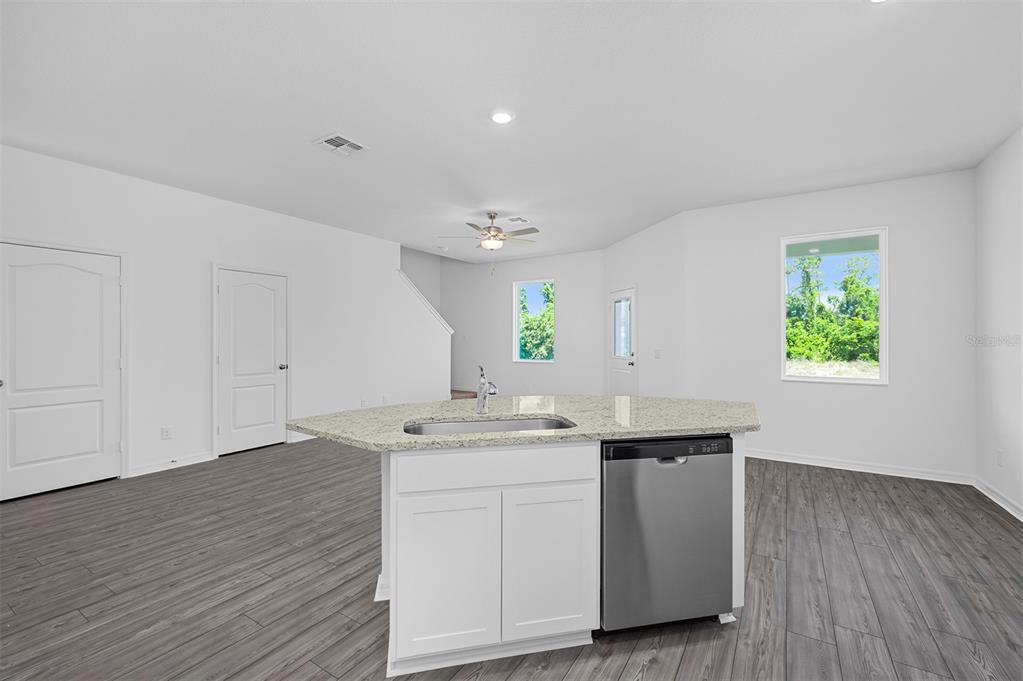 A kitchen island with a stainless steel dishwasher and sink sits in a white room — 556 BAY LEAF DRIVE, POINCIANA, FL