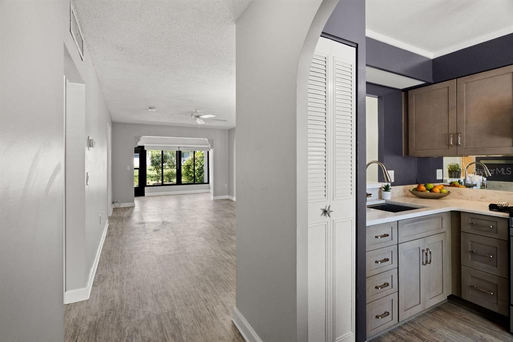 A view from a kitchen with grey cabinets looking into a living area with windows — 1276 MISSION CIRCLE UNIT 45A, CLEARWATER, FL