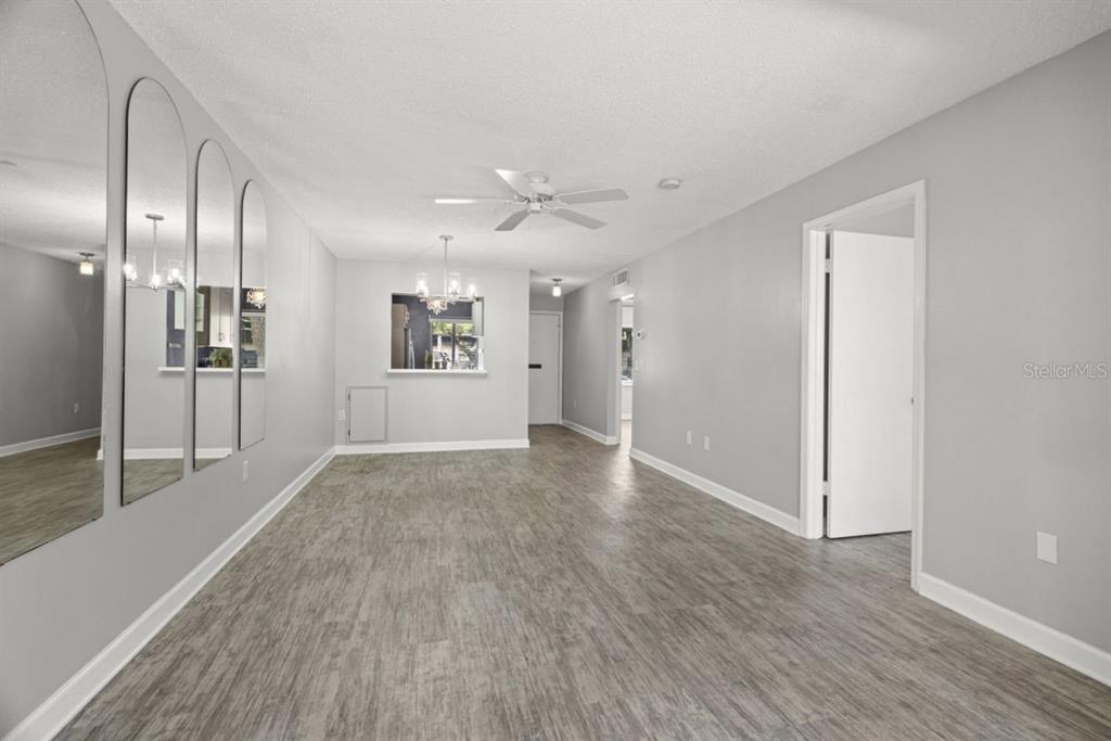 An empty living room features light gray walls, wood-look flooring, and a wall of mirrors — 1276 MISSION CIRCLE UNIT 45A, CLEARWATER, FL