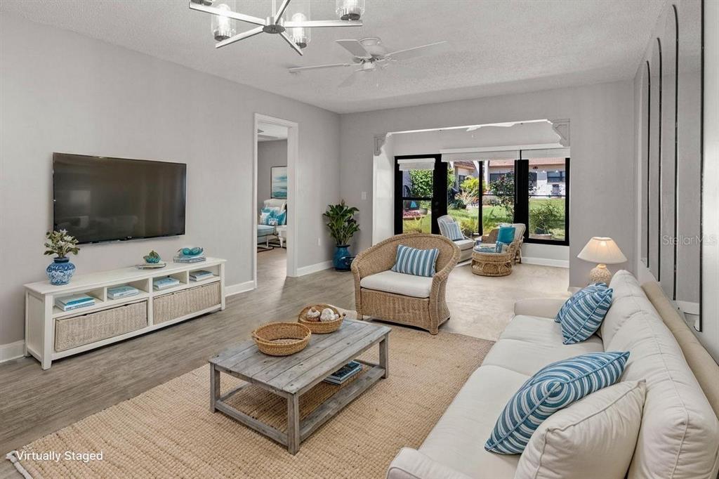 A living room features light gray walls, wood-look flooring, a white media console, and furniture — 1276 MISSION CIRCLE UNIT 45A, CLEARWATER, FL