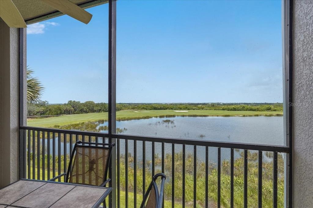 A screened-in balcony overlooks a pond and a golf course under a clear blue sky — 7705 GRAND ESTUARY TRAIL UNIT 305, BRADENTON, FL