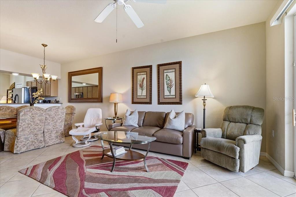 A living room features a brown leather sofa, a recliner, and a patterned area rug — 7705 GRAND ESTUARY TRAIL UNIT 305, BRADENTON, FL