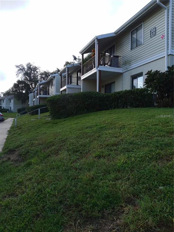 A multi-story apartment building with balconies sits above a grassy slope — 306 CHEROKEE COURT UNIT F, ALTAMONTE SPRINGS, FL