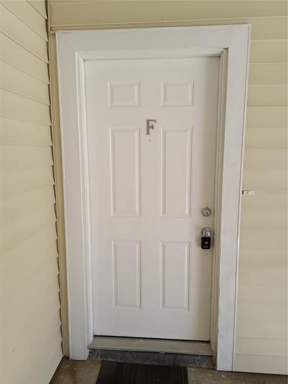 A white exterior door labeled with the letter F is set within light-colored siding — 306 CHEROKEE COURT UNIT F, ALTAMONTE SPRINGS, FL
