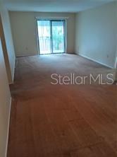 An empty room with brown carpet and a sliding glass door leading to a balcony — 306 CHEROKEE COURT UNIT F, ALTAMONTE SPRINGS, FL
