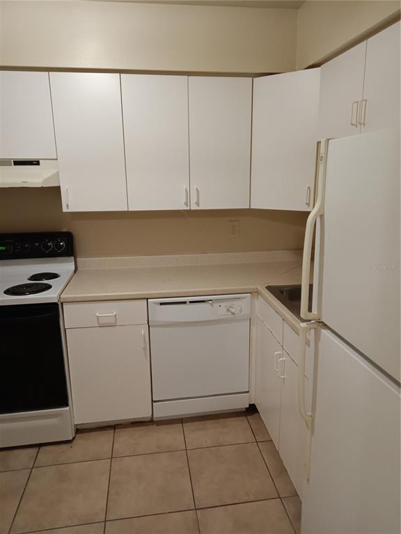 A kitchen features white cabinets, white appliances, a beige countertop, and tiled flooring — 306 CHEROKEE COURT UNIT F, ALTAMONTE SPRINGS, FL
