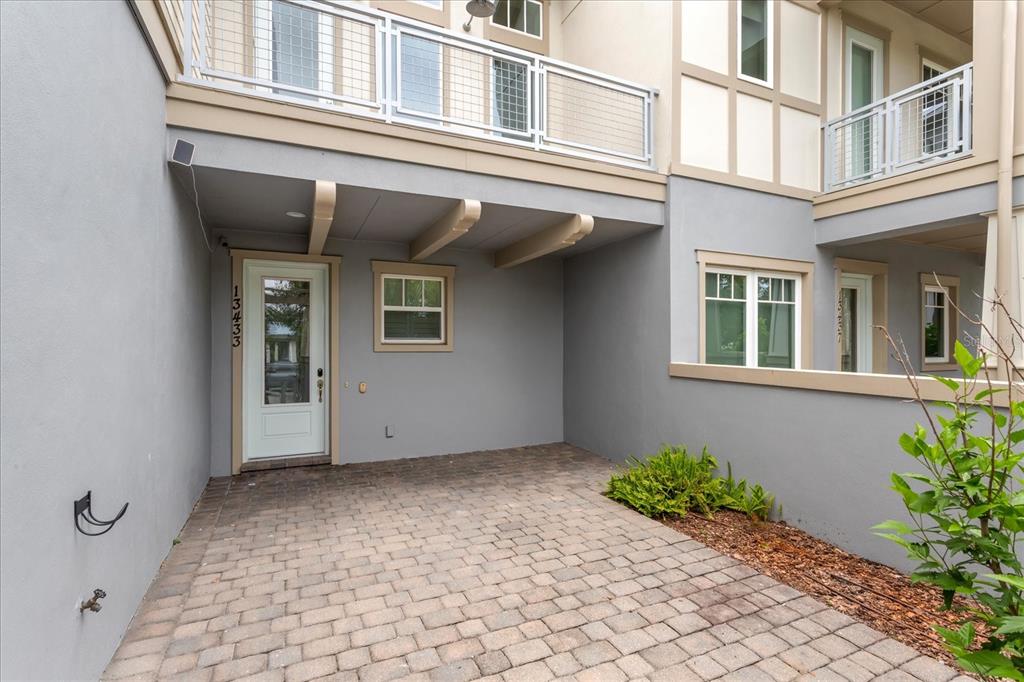 A paved patio area sits in front of a building entrance with a white door — 13433 GRANGER AVENUE, ORLANDO, FL