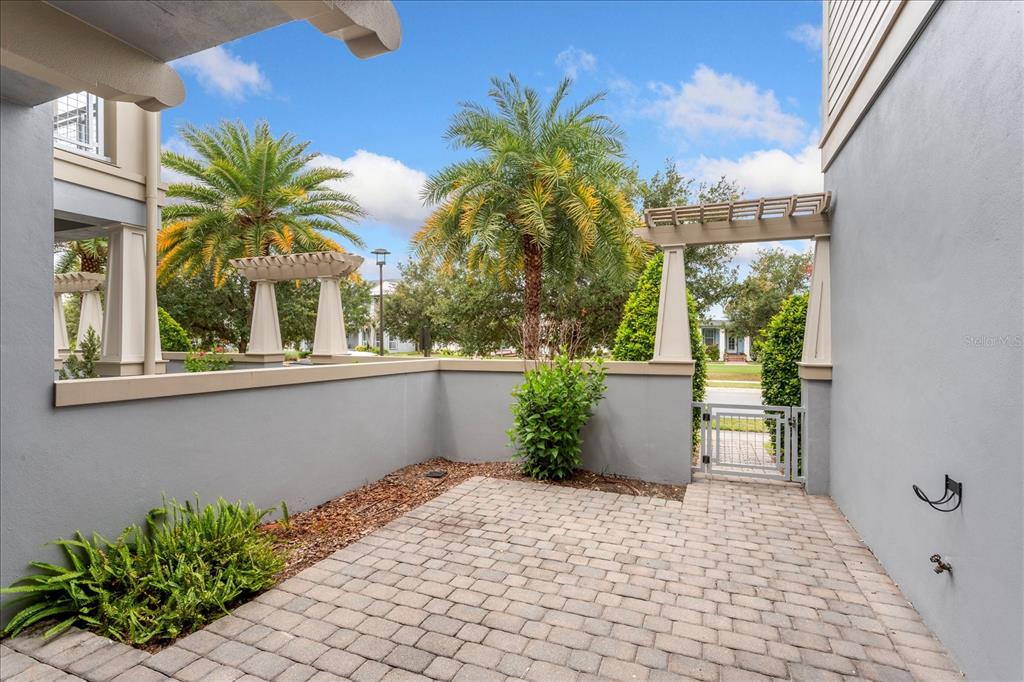 A paved patio area features a low wall, a gate, and palm trees — 13433 GRANGER AVENUE, ORLANDO, FL