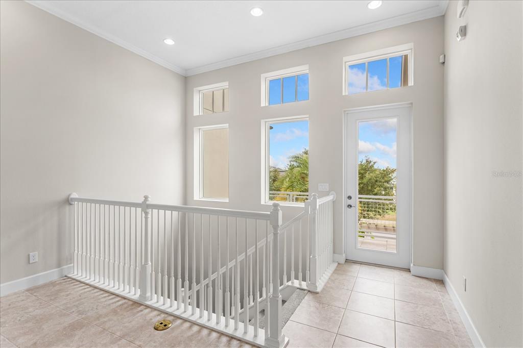 A landing area with tile flooring, a white railing, and a door leading outside — 13433 GRANGER AVENUE, ORLANDO, FL