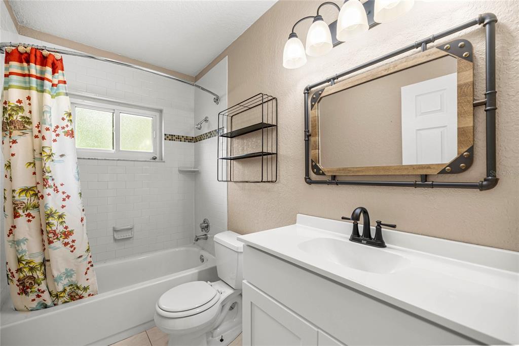A bathroom with a white vanity, a tub-shower combo, and an industrial-style pipe mirror — 2021 NW 13TH AVENUE, CRYSTAL RIVER, FL
