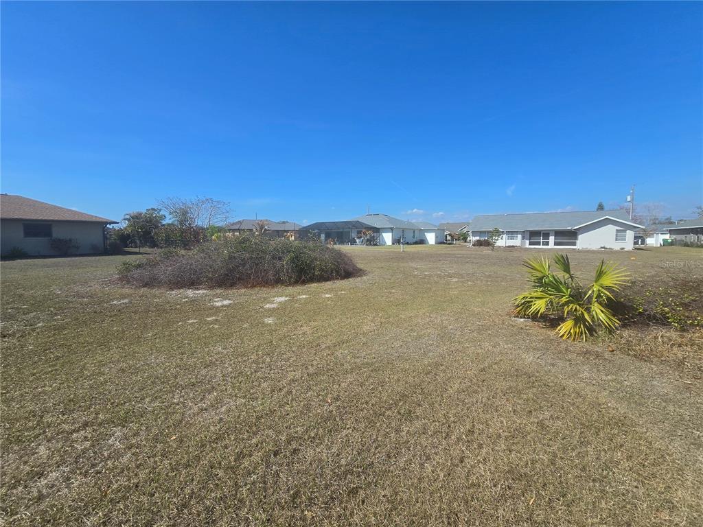 A large, grassy vacant lot features a central brush pile and a small palm plant — 154 SANTOS DRIVE, PUNTA GORDA, FL