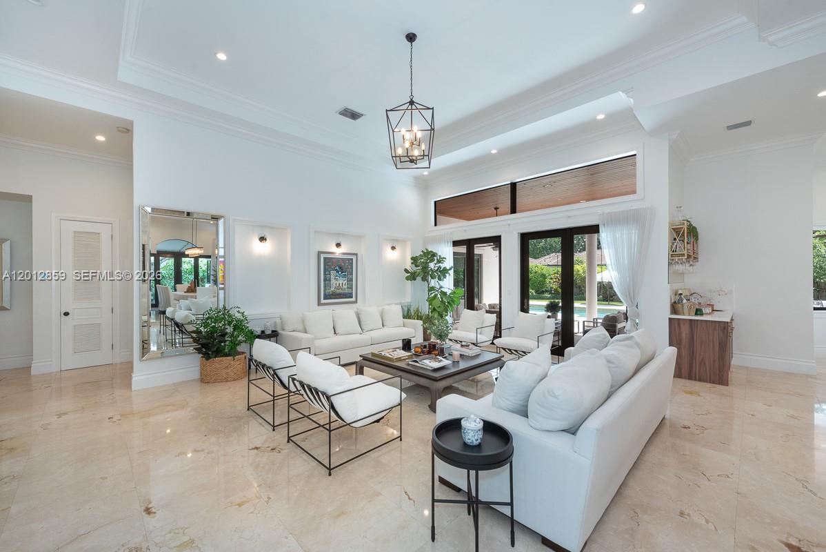 A bright living room features high ceilings, white sofas, a central chandelier, and large windows — 12311 SW 94th Ave, Miami FL 33176, MIAMI, FL