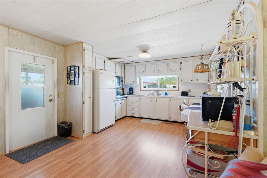 A kitchen with white cabinets, light wood-look flooring, and a white refrigerator — 64 RACHEL DRIVE, TARPON SPRINGS, FL