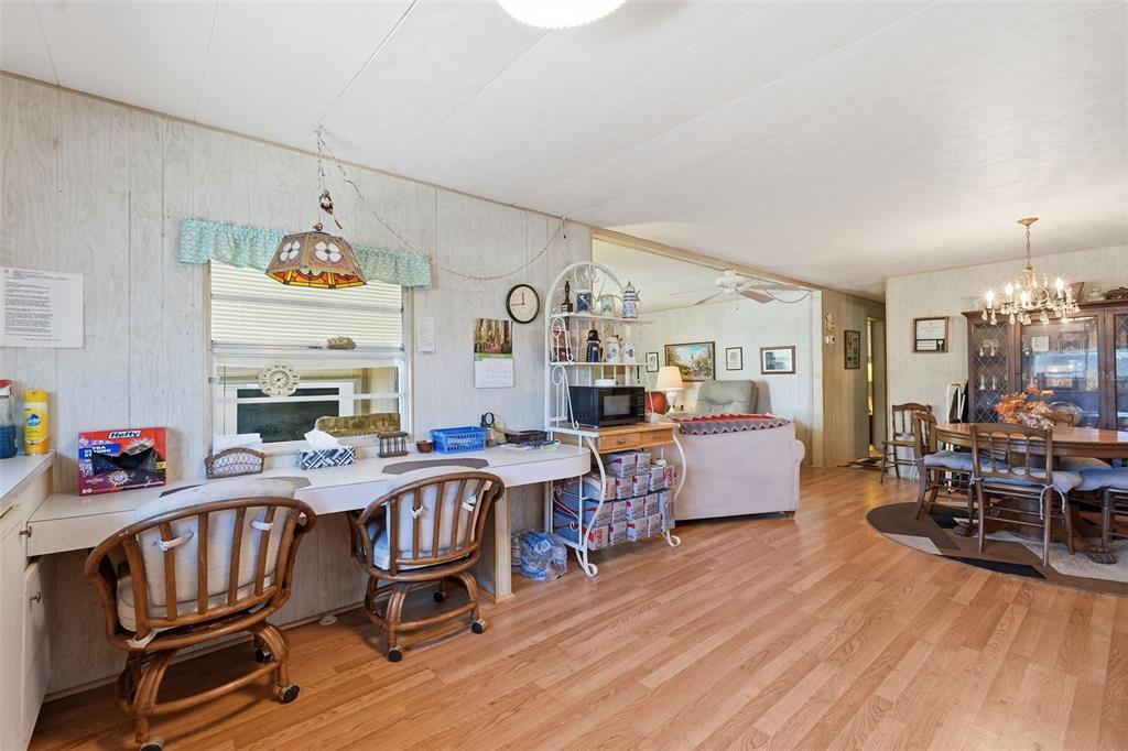 A living and dining area features wood-look flooring, wood-paneled walls, and a built-in desk — 64 RACHEL DRIVE, TARPON SPRINGS, FL