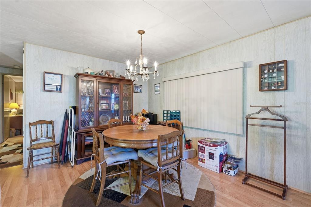 A dining room features a round wooden table, a china cabinet, and a chandelier — 64 RACHEL DRIVE, TARPON SPRINGS, FL