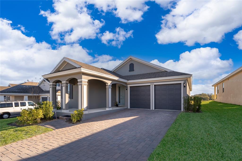 A single-story house with a paved driveway, two-car garage, and a covered front porch — 2060 KEYSTONE PASS BOULEVARD, MINNEOLA, FL