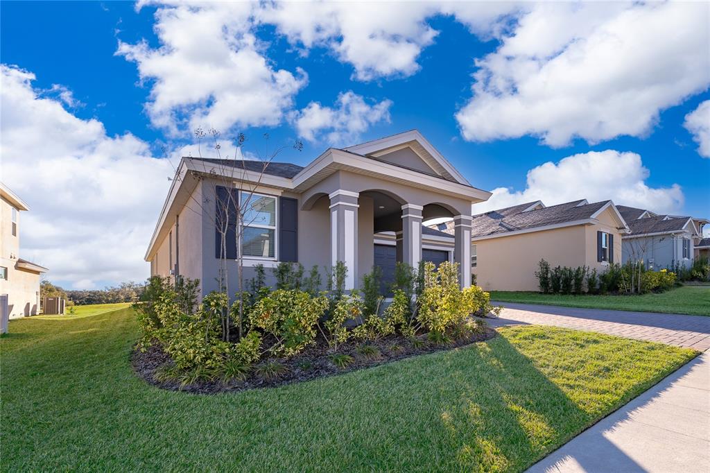 A gray single-story house with a covered front porch and a landscaped front yard — 2060 KEYSTONE PASS BOULEVARD, MINNEOLA, FL