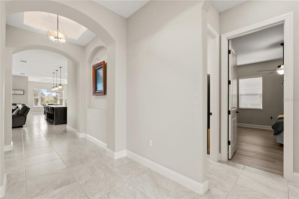 A tiled hallway leads to an open-concept kitchen and a bedroom with wood-look flooring — 208 HERON DRIVE, PALM COAST, FL