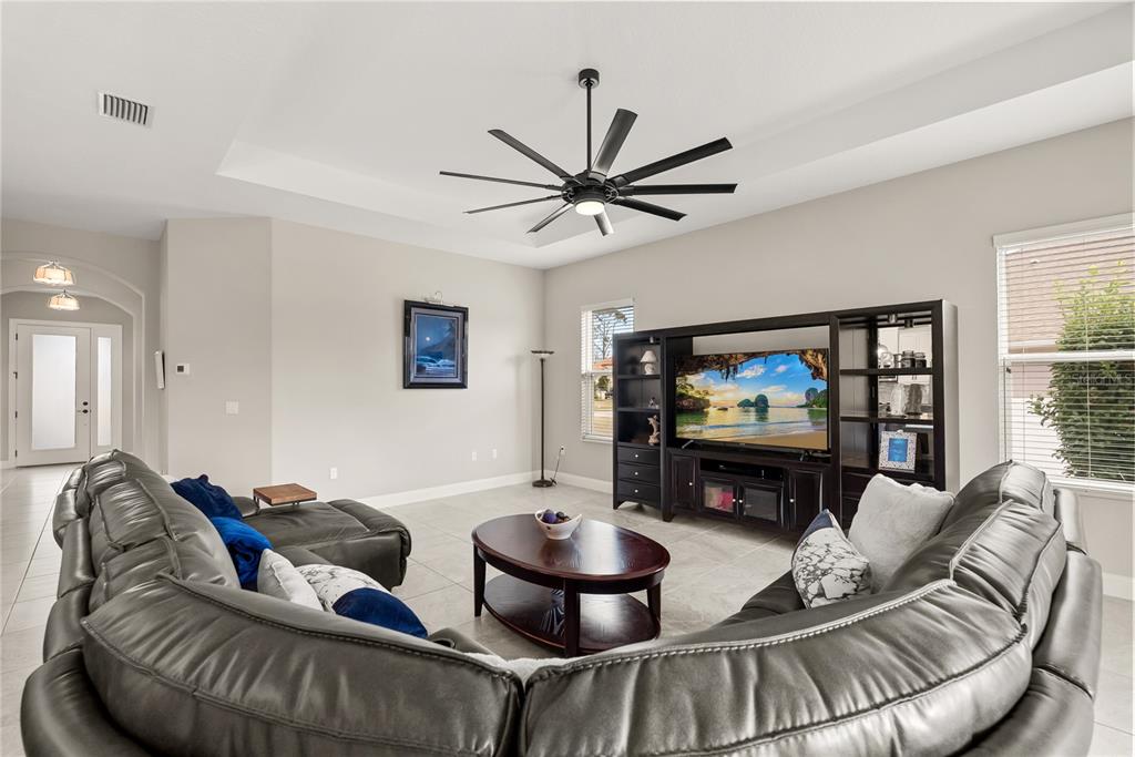 A living room features a large sectional sofa, a dark wood entertainment center, and a ceiling fan — 208 HERON DRIVE, PALM COAST, FL