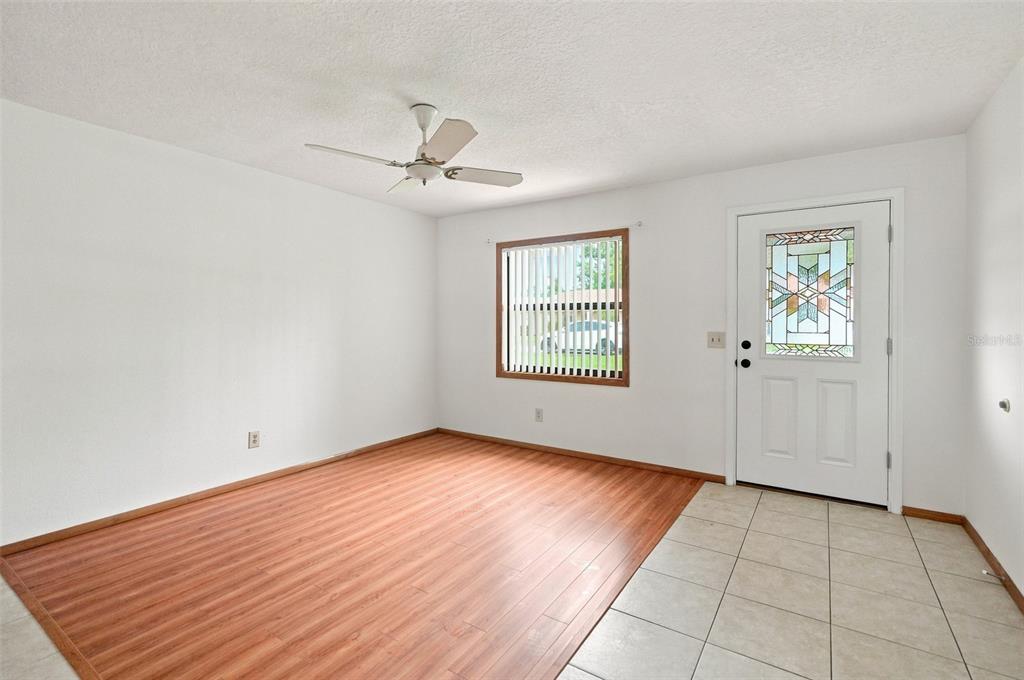 An empty room features wood-look laminate flooring, a ceiling fan, a window, and a door — 2151 MEREDITH DRIVE, SPRING HILL, FL
