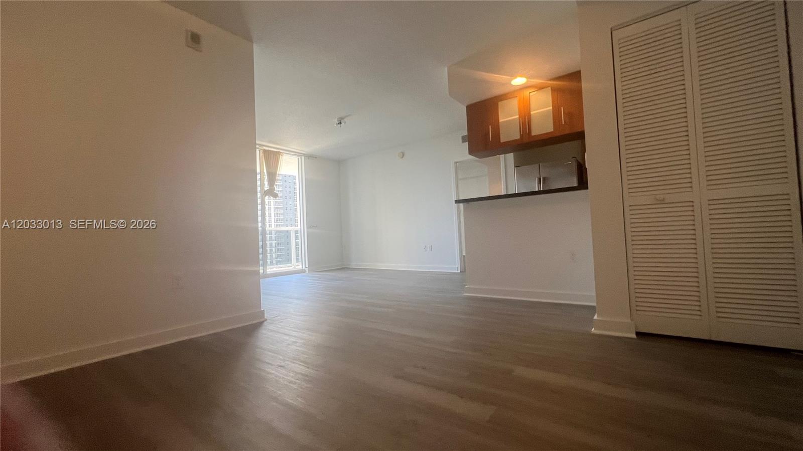 An open-concept living area features light wood-look flooring and a kitchen with dark cabinetry — 601 NE 23rd St # 1004, Miami FL 33137, MIAMI, FL
