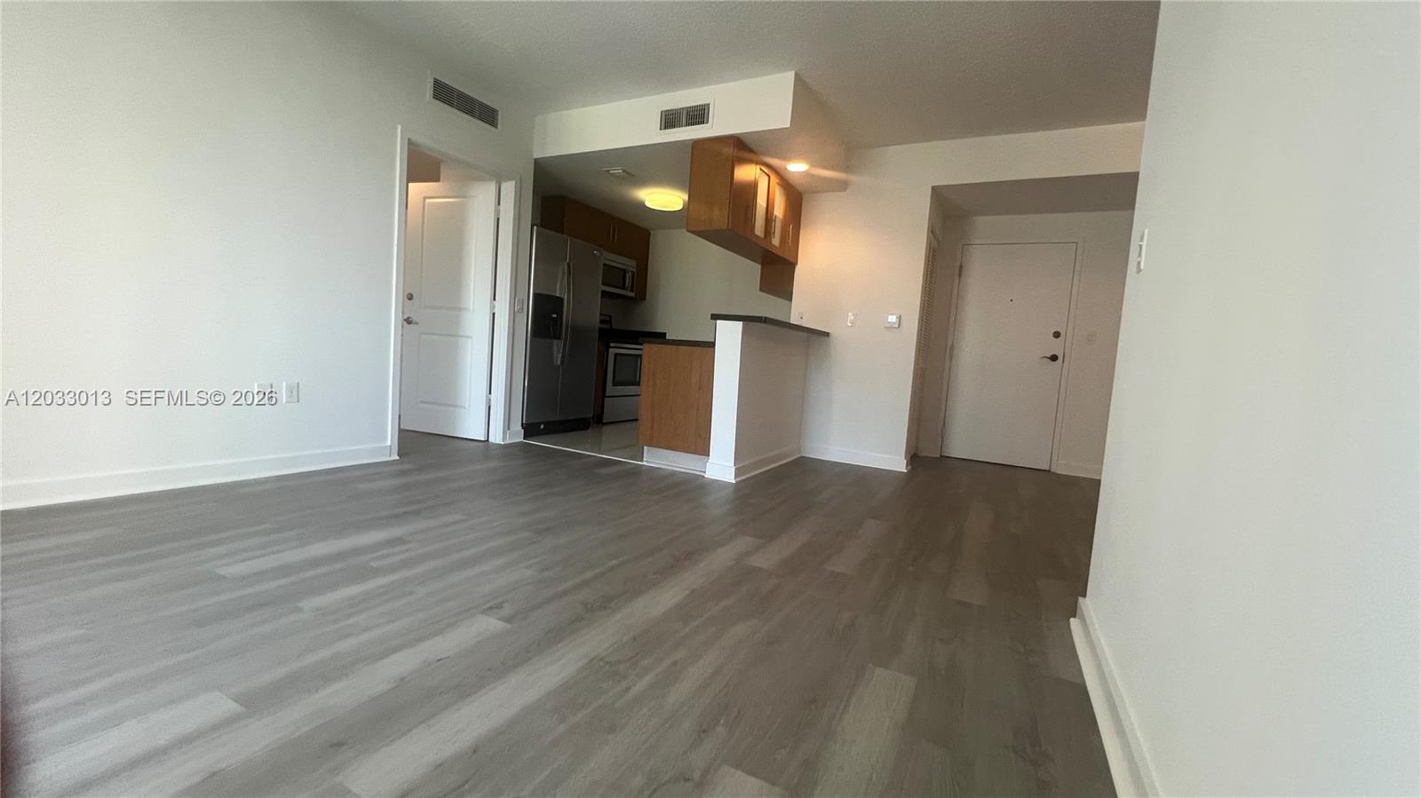 An open-concept living area features wood-look flooring, a kitchen with stainless appliances, and white walls — 601 NE 23rd St # 1004, Miami FL 33137, MIAMI, FL
