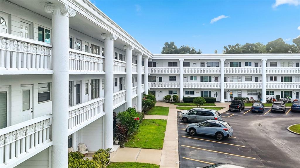 An exterior view of a multi-story apartment building with white columns and a parking lot — 2454 AUSTRALIA WAY E UNIT 32, CLEARWATER, FL