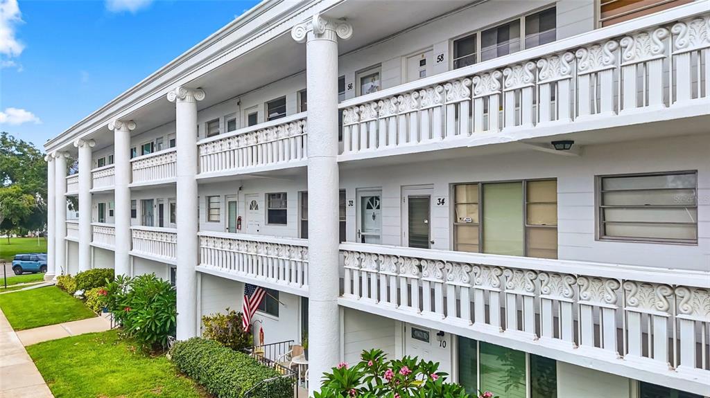 A multi-story apartment building features white exterior walls, large columns, and decorative balcony railings — 2454 AUSTRALIA WAY E UNIT 32, CLEARWATER, FL